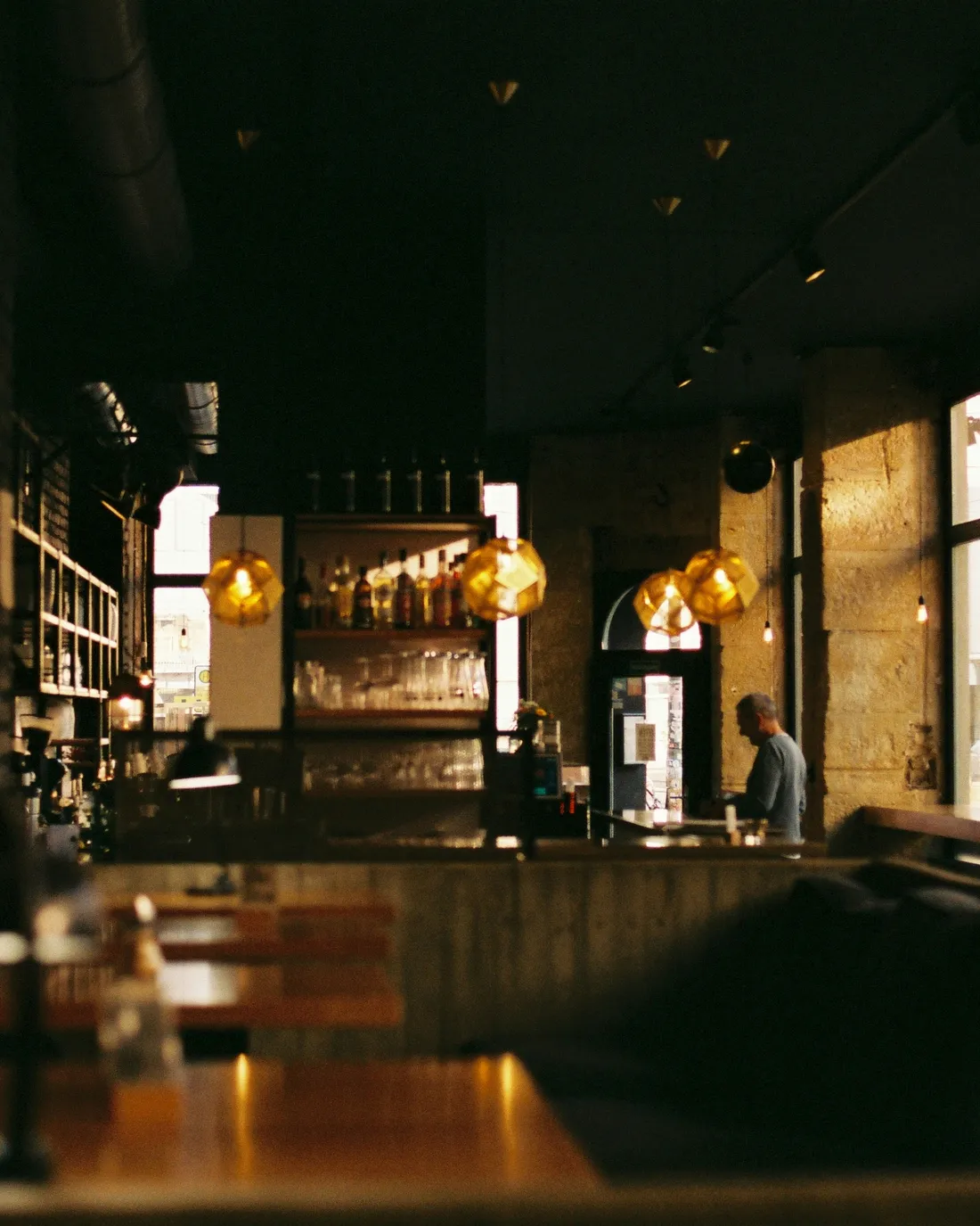 The dining room at night, lit by low brass pendants over the bar